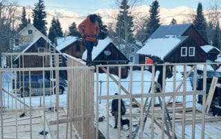 Construction site with workers in orange jackets in a snowy mountain area