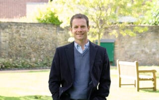 Man wearing dark blazer in a serene park-like setting