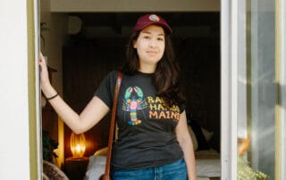 Person wearing a maroon cap and a 'bar harbor maine' t-shirt standing at a doorway