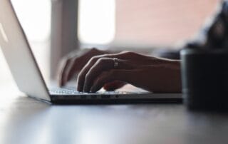 Close-up of hands typing on a laptop keyboard