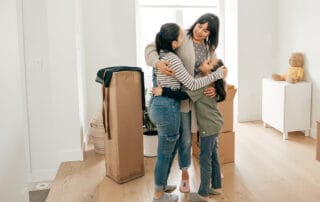 Family hugging in their new home, surrounded by moving boxes