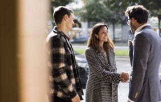Image of three professionals interacting in an urban outdoor setting.