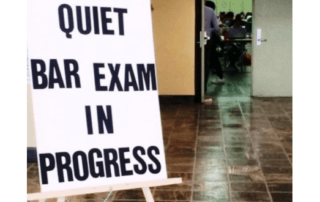 Sign indicating bar exam in progress with people seated in the background