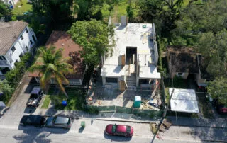 A view of a suburban area under construction, showcasing a partially built house with surrounding materials and completed homes.