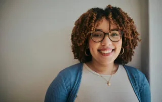 Portrait of a professional and approachable person with curly hair and glasses