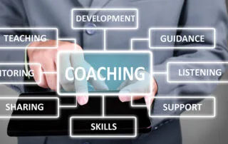 Image of person in a suit with a tablet surrounded by coaching-related terms.