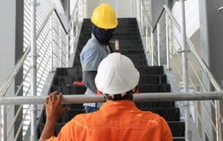Construction workers in safety helmets assembling scaffolding on an indoor stairway