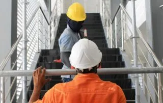 Construction workers in safety helmets assembling scaffolding on an indoor stairway