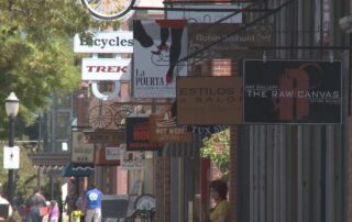 Lively downtown street lined with small businesses and hanging shop signs