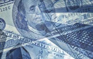 Overlay of u. S. Hundred‑dollar bills with modern glass office buildings, symbolizing finance and investment.