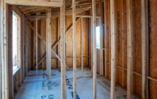 Interior view of a house under construction showing exposed wooden wall studs and framing