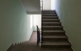 Interior staircase with tiled steps and metal handrail in a bright corridor