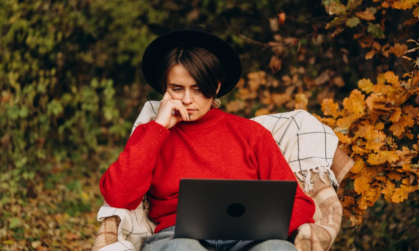 Person working on laptop in autumn park