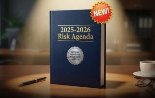 New “2025–2026 risk agenda” official guidebook for insurance agents standing on a desk with a pen, coffee cup, and glasses.