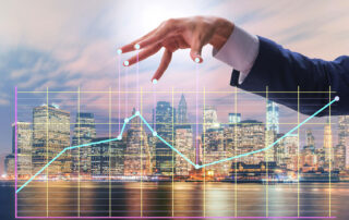 Businessperson’s hand manipulating a rising financial graph over a city skyline at night