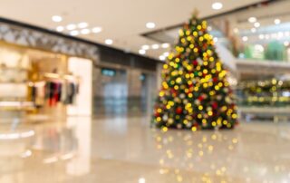 Blurred view of a decorated christmas tree with lights inside a modern shopping mall.