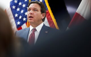 Florida’s Property Tax Showdown Could Trigger A Sudden Surge In Home Prices 6 Man in a suit speaking in front of american flags