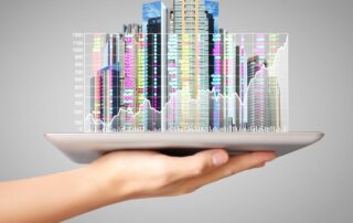 Hand holding a digital tablet with a holographic city skyline and rising financial stock chart.