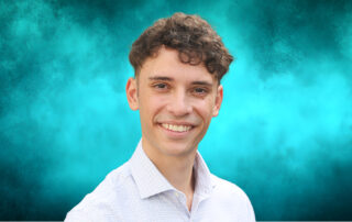 Smiling young man in a light dress shirt against a teal textured background