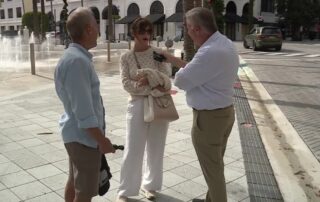Street interview with a woman and two men on a city plaza near a fountain
