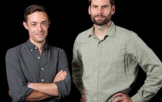 Ai-Powered Excavators? Gravis Robotics Secures $23M To Tackle Construction’s Growing Labor Crisis 4 Two men standing side by side against a black background, both wearing long-sleeve button-down shirts and looking at the camera.