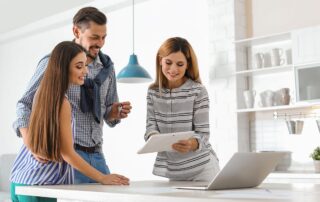 Happy couple meeting with real estate agent in modern kitchen and receiving house keys