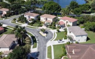 Aerial view of a quiet suburban cul‑de‑sac with single-family homes, palm trees, and a nearby lake