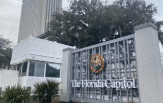 Sign and entrance to the florida capitol complex with state seal and surrounding trees.
