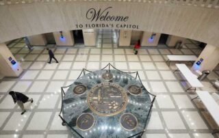 Welcome lobby inside the florida state capitol building featuring the great seal of florida on the floor and people walking through the rotunda.
