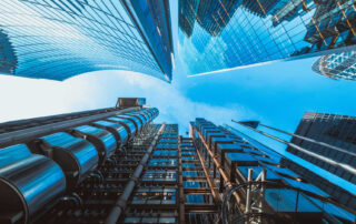 Looking up at modern glass and steel skyscrapers against a clear blue sky in a financial district.