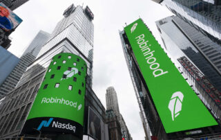 Robinhood and nasdaq logos displayed on large green digital billboards in times square, new york city.