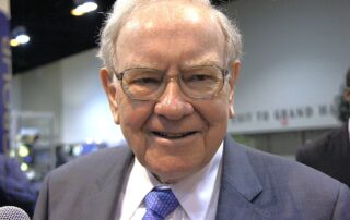 Smiling elderly man in a suit and tie at an indoor event