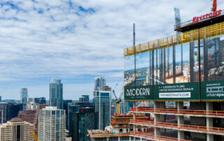 A high-rise residential tower under construction in downtown austin, texas, featuring a large billboard for the modern austin residences above the city skyline.