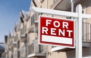 Red “for rent” sign hanging in front of modern apartment buildings