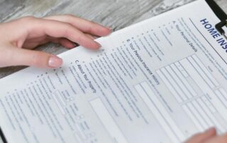 Person reviewing and filling out a home insurance application form on a clipboard.