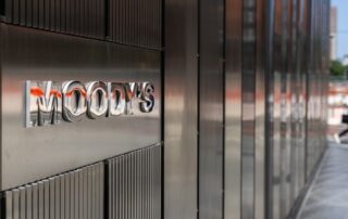 Sign reading “moody’s” on the exterior wall of a modern metal-clad office building.