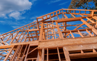Wooden framing of a new house under construction against a bright blue sky.