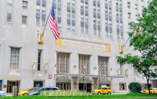 Facade of the waldorf astoria hotel with american flag and yellow taxis in front