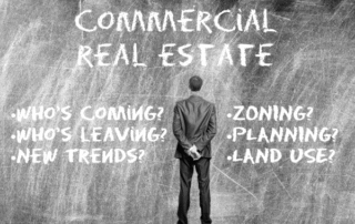 Businessman standing in front of a chalkboard with the words “commercial real estate” and questions about trends, zoning, planning, and land use.