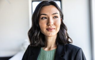 Portrait of a young professional woman in a blazer looking to the side in a bright office