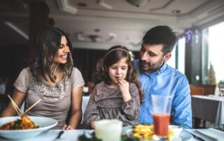 Family with young child enjoying a meal together at a restaurant table