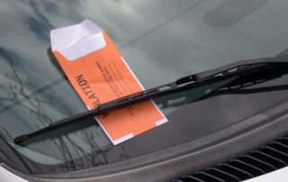 Parking violation ticket placed under a car’s windshield wiper